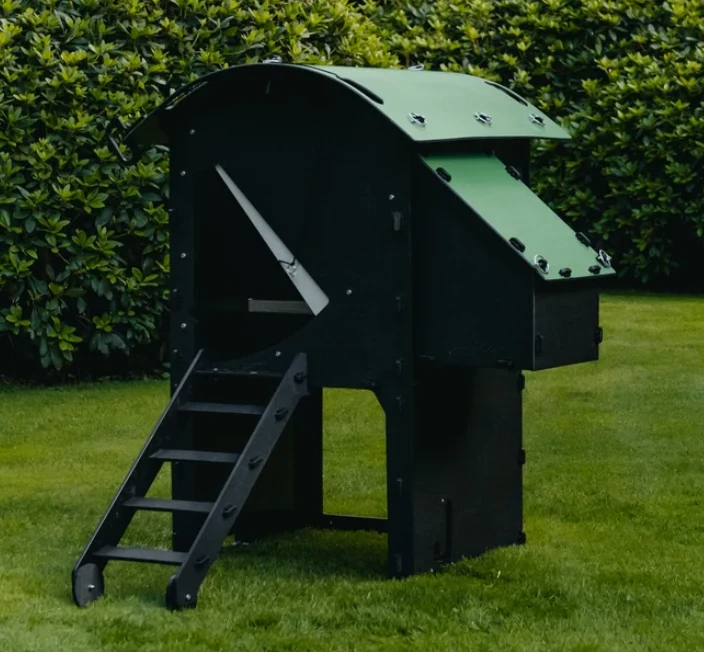 Green raised plastic chicken coop with an access ladder on a lawn